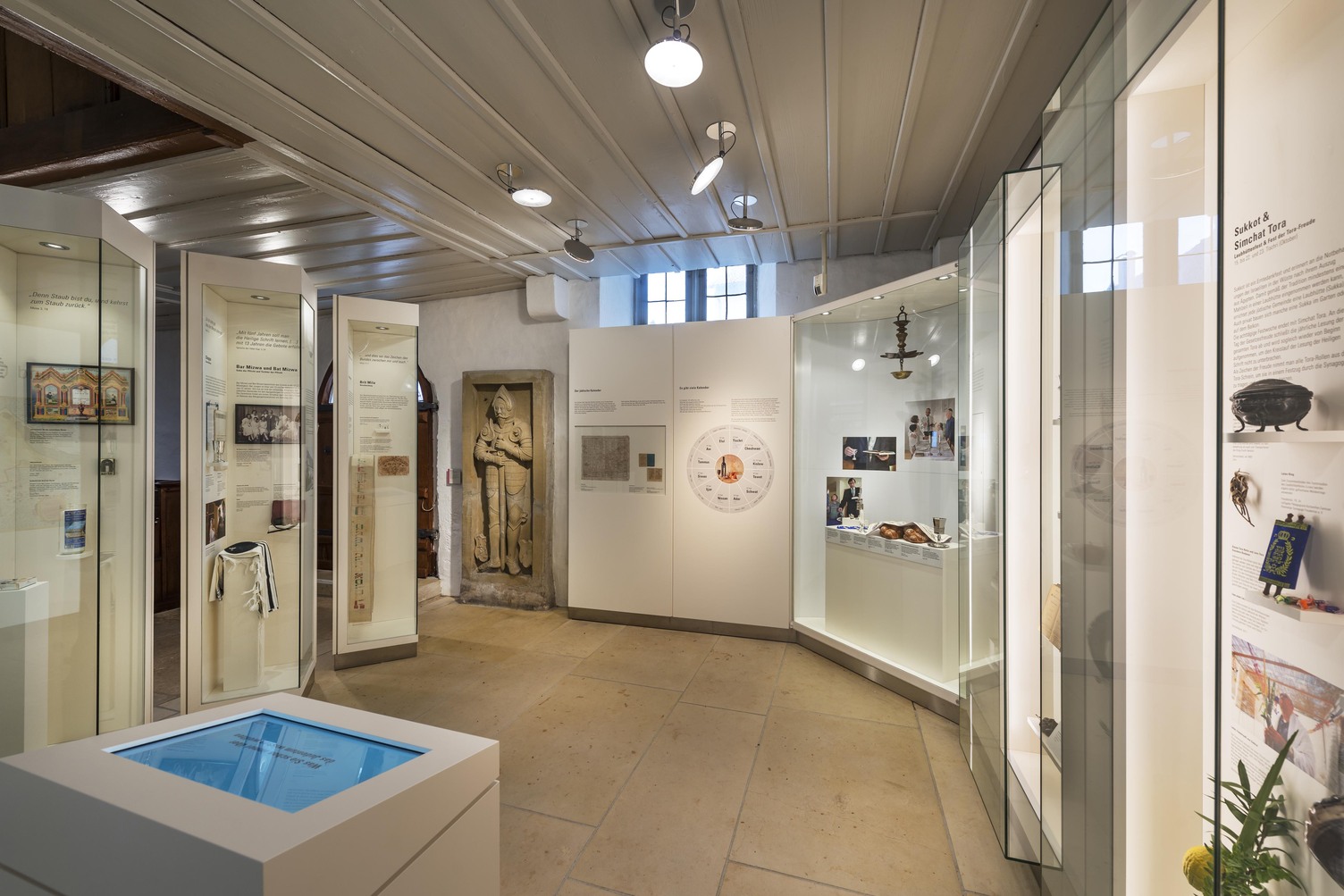 Ausstellungsbereich mit vielen Vitrinen mit innenliegenden Vitrinenlicht. Atmosphäre unterstützt und Aufhellung des Grundlichtes durch AVVENI PURE CEILING: Halbeinbauleuchten in edlem polierten Aluminium mit beweglichen runden flachen Leuchtenköpfen. | © Rose Hajdu, Stuttgart