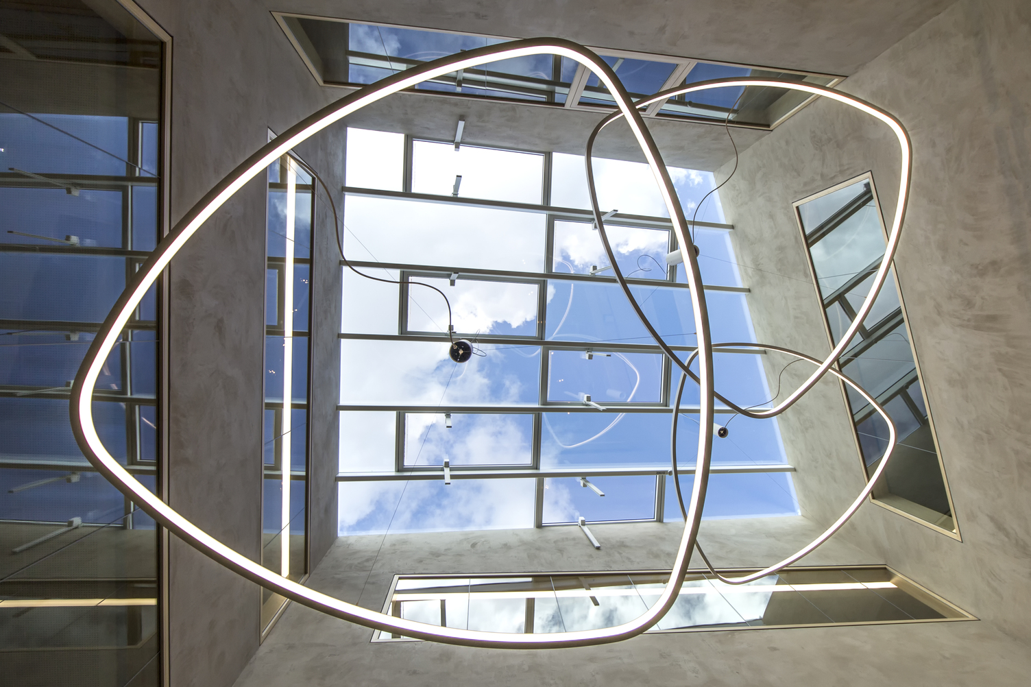Central view under the SOFT DELTA I luminaire from SATTLER mounted on a pendant canopy under a glass roof,