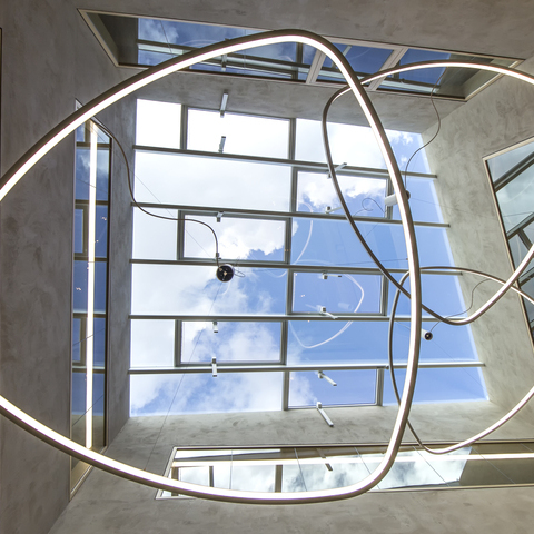 Central view under the SOFT DELTA I luminaire from SATTLER mounted on a pendant canopy under a glass roof,