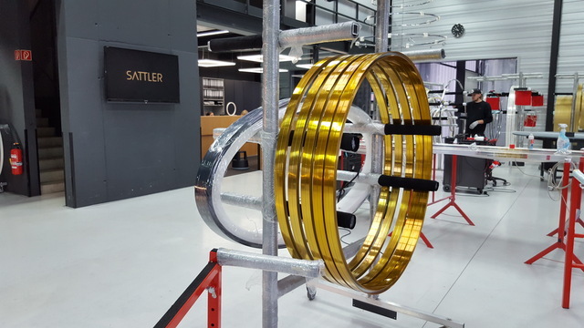 SATTLER luminaire production hall featuring several gold-glazed ring lights mounted on a single stand. | © SATTLER