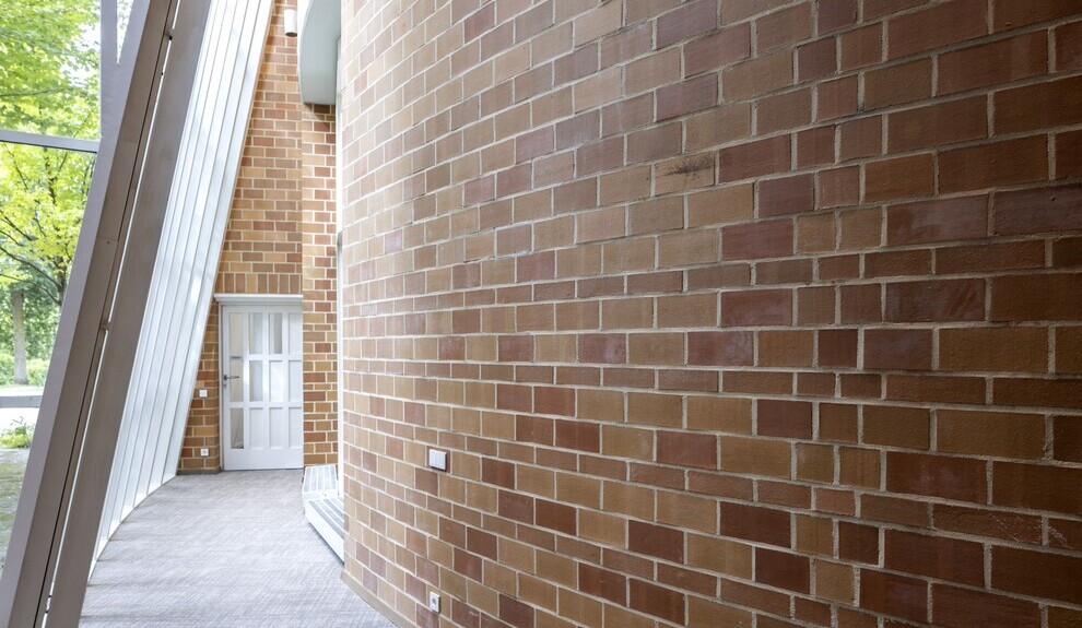 Architektonische Vielfalt im Forum Kreis Viersen Im Forum Kreis Viersen. Ein Flur - links davon eine schräge Glaswand, rechts davon eine runde Backstandwand. Flur führt auf eine weiße Tür.