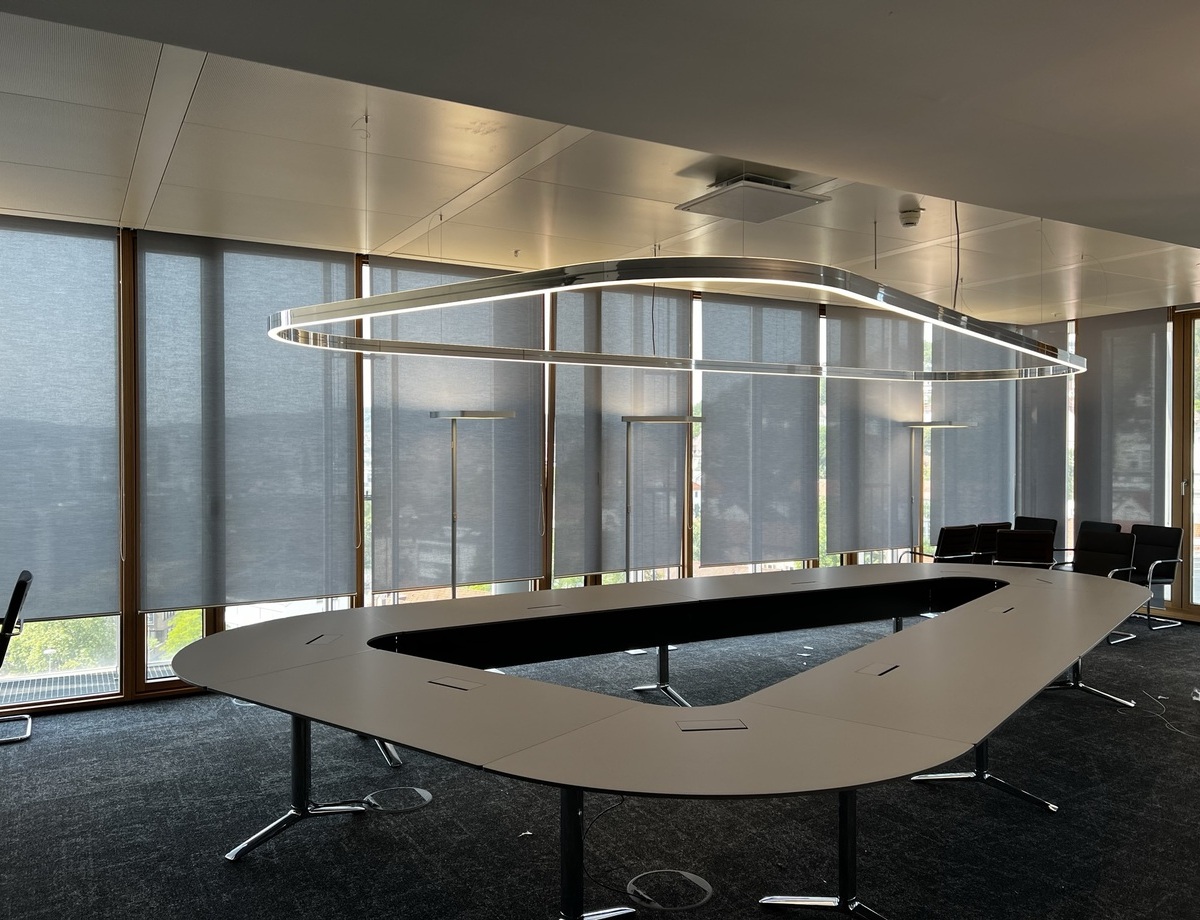 Wankelförmiger Konferenztisch in der LBBW Stuttgart mit maßgefertigter DUETTO Ringleuchte, perfekte Anpassung an Wankel-Tischform