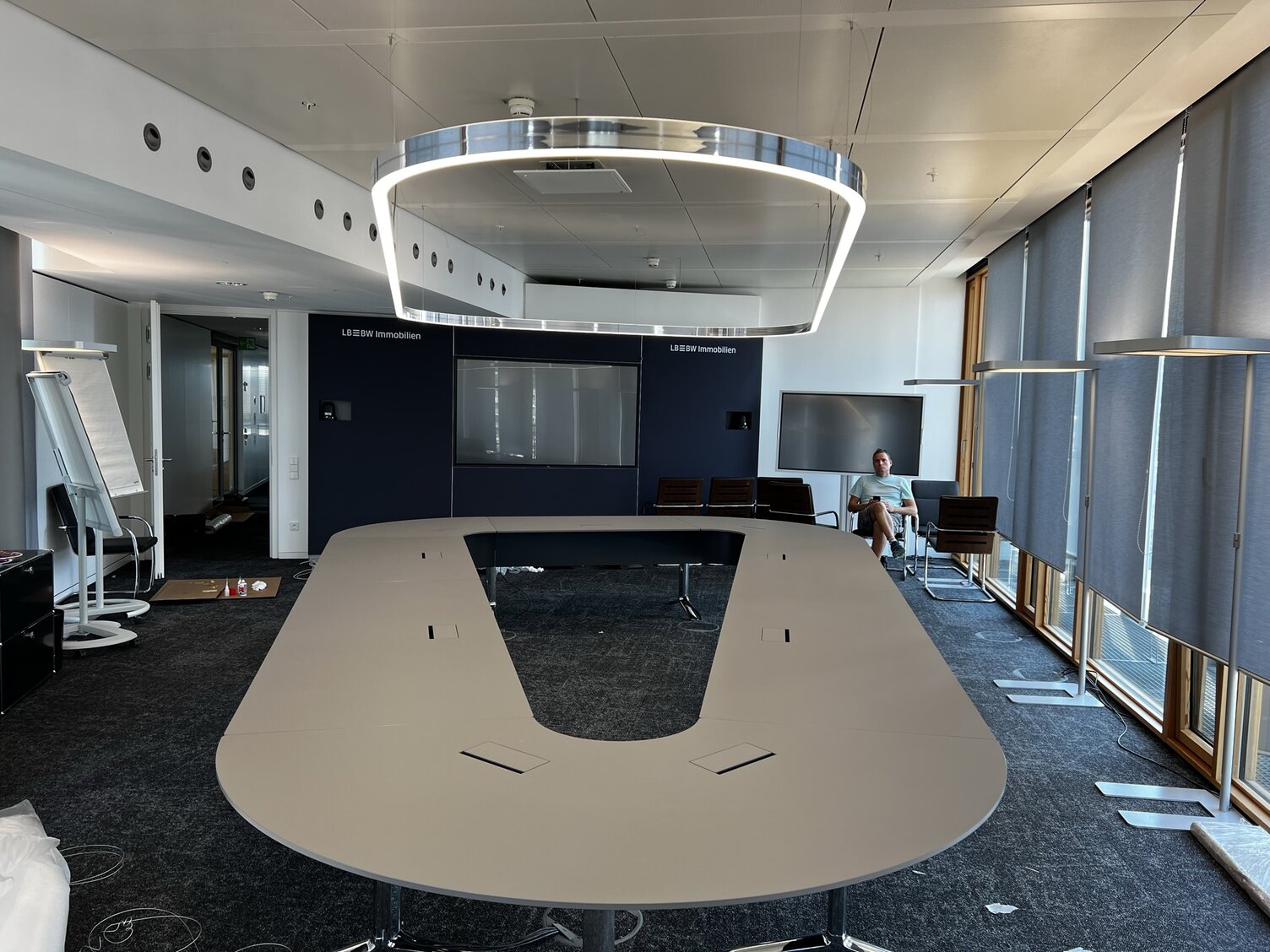Individuelle Leuchtenlösungen - DUETTO in geschlossener U-Form - über formgleichen Konferenztisch U-förmiger Konferenztisch in der LBBW Stuttgart mit maßgefertigter DUETTO Ringleuchte in Aluminium poliert, die die Form des Tisches aufgreift.