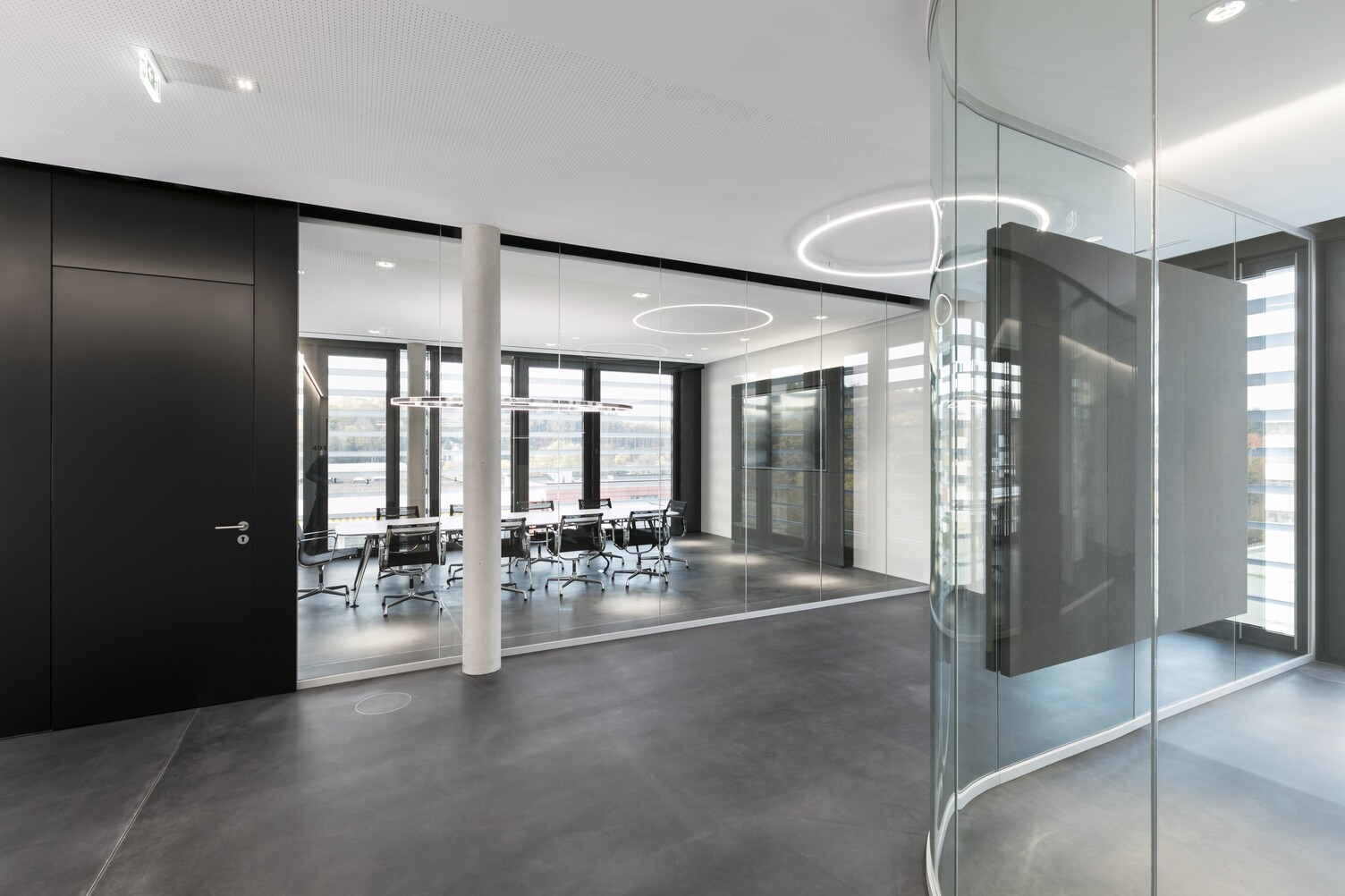 corridor area with a Slim arranged directly. In the glass office behind, a Doppio Ellipse was suspended above a meeting table.