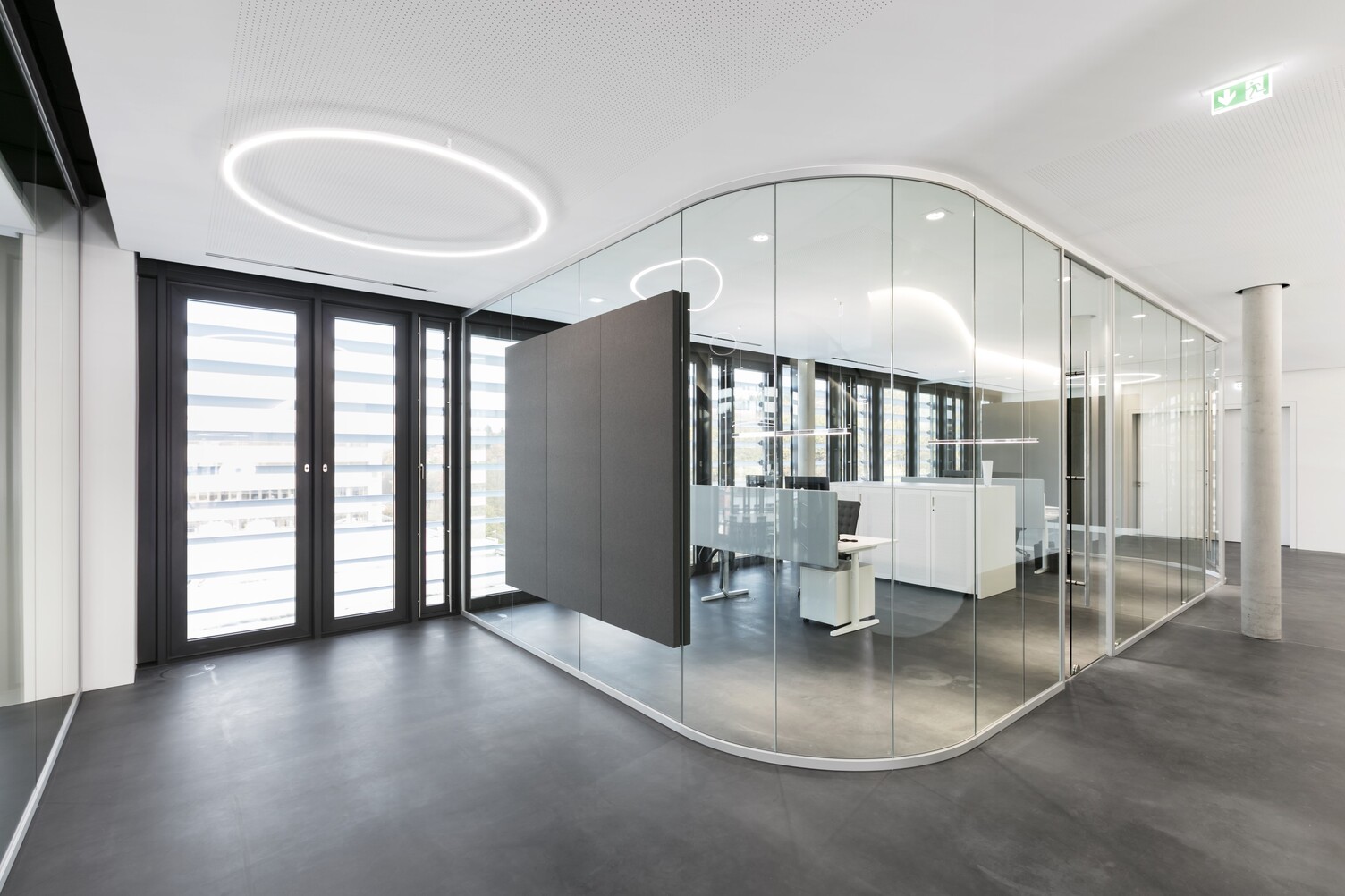 Slim Direkt from SATTLER mounted directly to the ceiling in a corridor. In the background are glass offices with SATTLER Doppio ellipses and BE spotlights. 