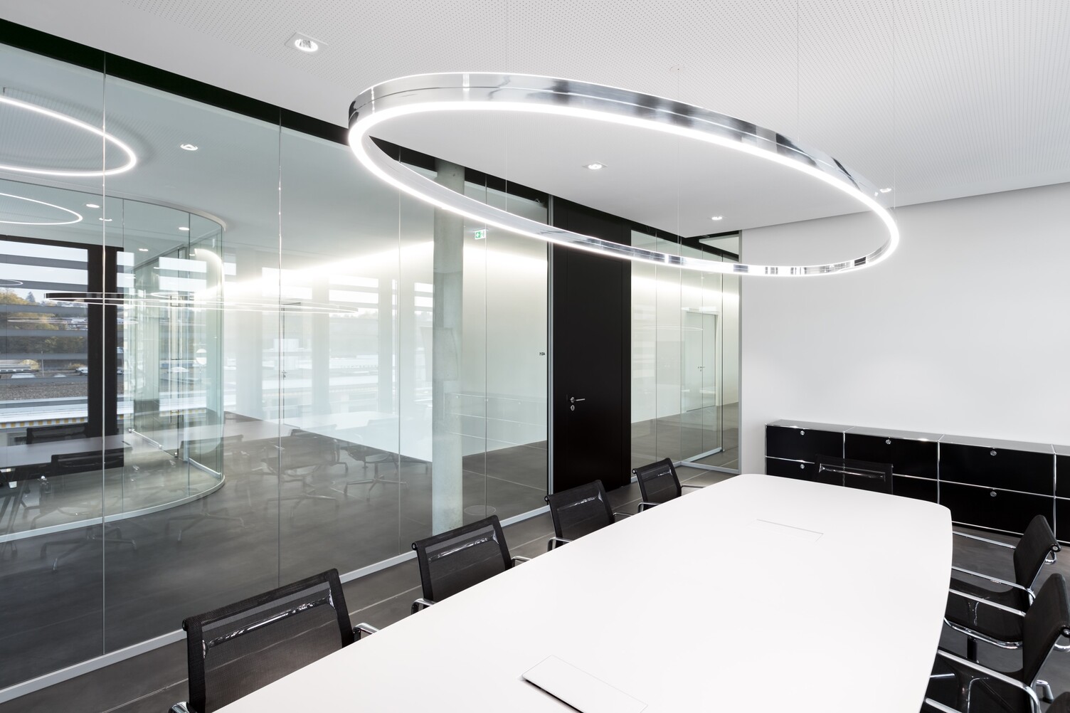 Doppio Ellipse with BE3 spotlights, each from SATTLER, arranged in a glass meeting room above a white table