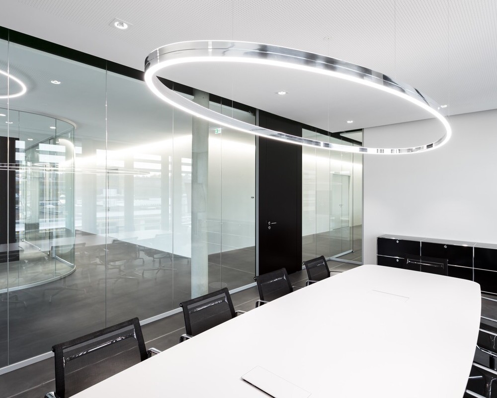 Doppio Ellipse with BE3 spotlights, each from SATTLER, arranged in a glass meeting room above a white table