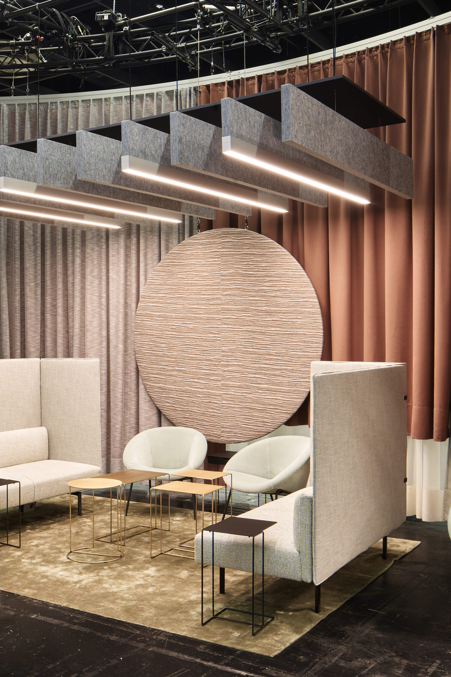 Akustisch wirksame Raum-in-Raum-Lösung mit BAFFELLEUCHTEN | © Philip Kottlorz Messestand ORGATEC 2024 von Walter Knoll mit hellen Polstermöbeln und kleinen Sofa-Tischen, darüber sind mehrere lineare Baffelleuchten (BAFFELLEUCHTE) und reine lineare akustisch wirksame Baffeln (ACOUSTIC BAFFLE) in grau abgependelt. | © Philip Kottlorz