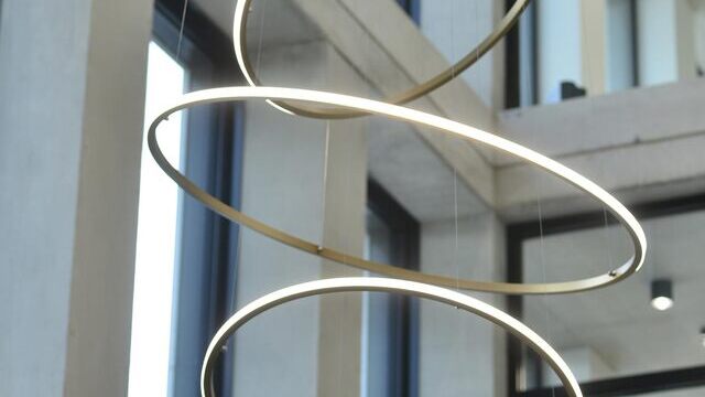 Großaufnahme verschiedener schmaler Ringleuchten SLIM OUT, die in unterschiedlichen Höhen und in unterschiedlichen Winkeln im Raum untereinander pendeln. Installation von SATTLER im Foyer Monari Headoffice | © monari