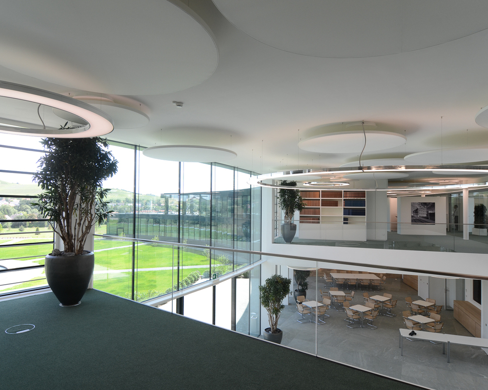 Anello und Acoustic Lights von SATTLER in Kombination in einem Foyer | © SATTLER | Werbe-und Medienagentur Mohring View from a gallery into a modern foyer with a glass front. The foyer was fitted with Anello luminaires and fabric-covered acoustic panels, all from SATTLER. | © SATTLER | Werbe-und Medienagentur Mohring