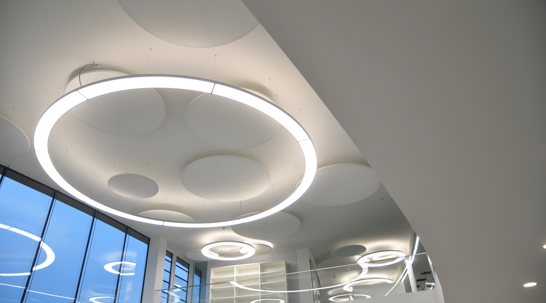 Runde Pendelleuchte Anello 6m und Acoustic Panel im Foyer der Münzing Chemie | © SATTLER | Werbe-und Medienagentur Mohring In einem Foyer mit Blick in Richtung einer 6m Anello in Aluminium poliert und parallel dazu montierten Akustik Panel jeweils von SATTLER. | © SATTLER | Werbe-und Medienagentur Mohring
