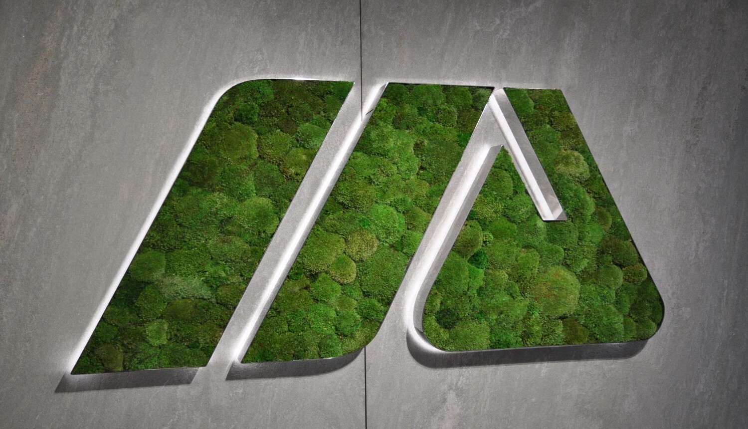 custom luminaire with moss surface integrated as branded logo element in architecture