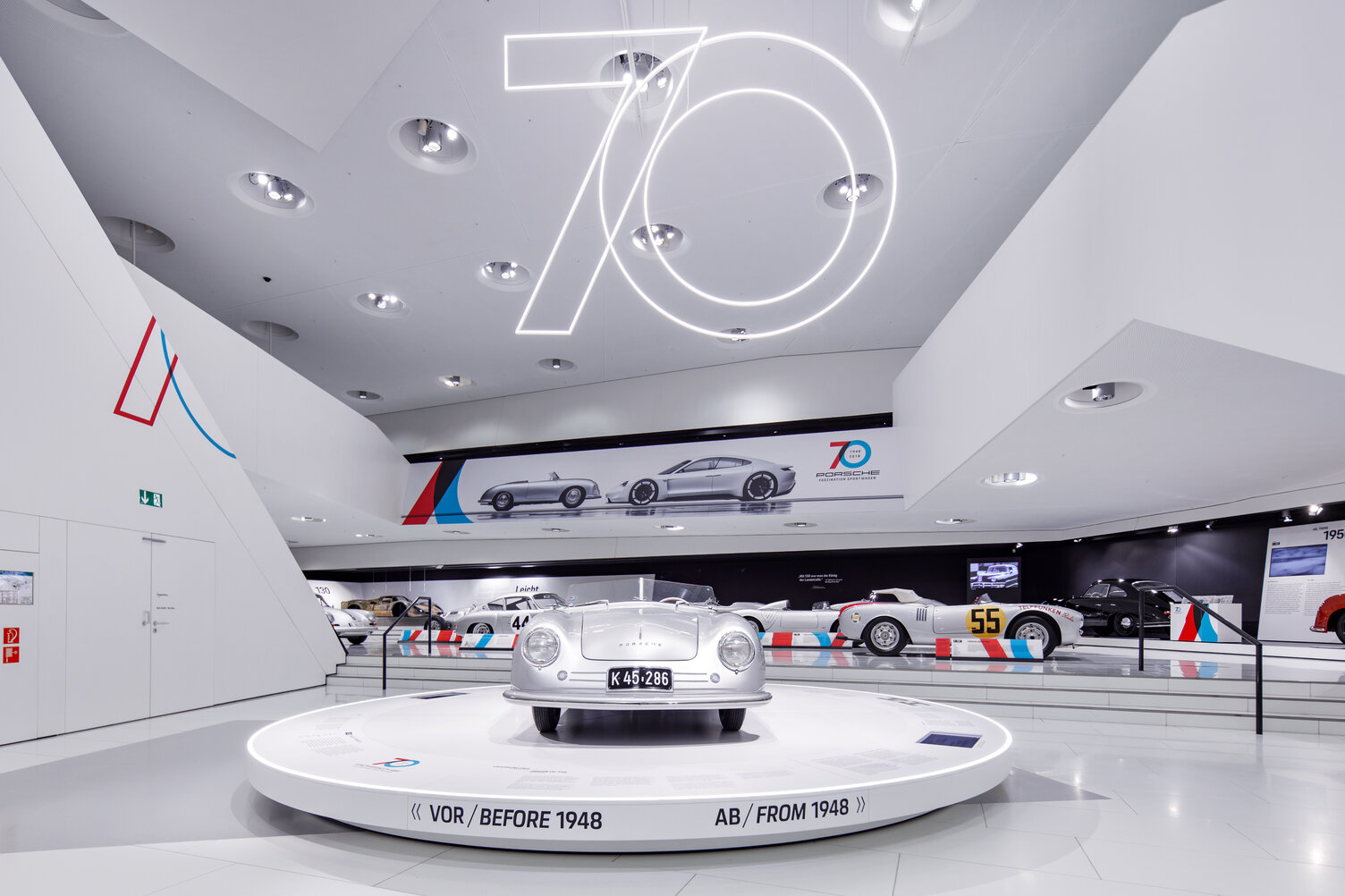 Innenansicht des Porsche Museums in Stuttgart mit der Paris-Dakar Ausstellung und moderner Beleuchtung von Sattler zum 70 jährigen Jubiläum von Porsche Sportwagen. Für die Fenster wurde ein beleuchteter Rahmen als Bbeleuchteter Bilderrahmen mit unsererm CoveLighting in einer Sonderausführung geplant, entwickelt und montiert. Hier in einer anderen Ansicht fotografiert.  | © Tobias Fröhner Photography