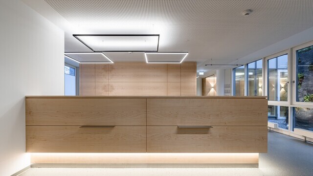Beleuchtete Empfangstheke mit rechteckigen Lichtinstallationen | © ARCHITEKTURIMBILD, Bernhard Tränkle
