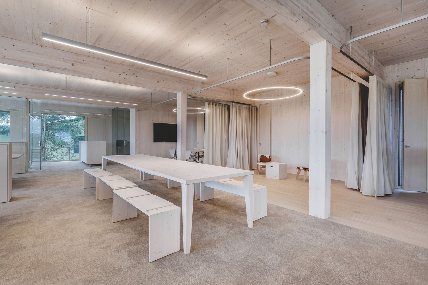 Heller Büro- und Besprechungsbereich im Schumann Project mit linearen Leuchten und Ringleuchten unter einer Holzdecke