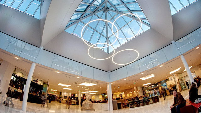 Multiple SLIM ring luminaires in different heights form a striking lighting object under the glass roof of Helsinki shopping mall.