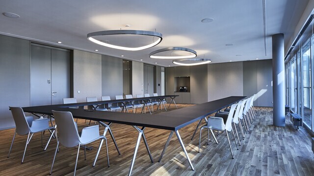 Elegant event space with large-format ring pendant lights and modern seating for meetings and conferences. | © Fotografie SUL – Sven Lorenz