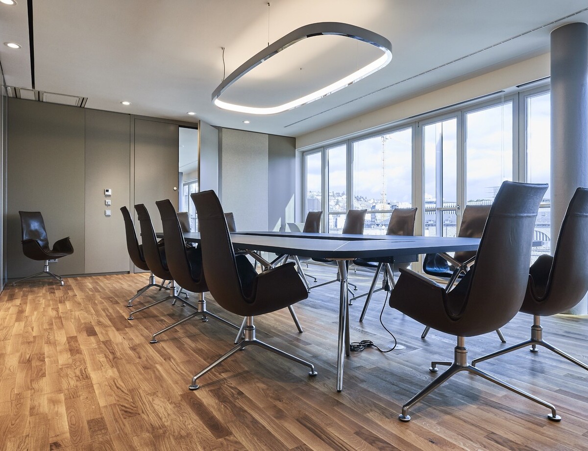 Moderner Besprechungsraum mit SATTLER Soft Delta und Soft Square Leuchten. Hochwertige Beleuchtung für Konferenzräume mit natürlicher Ausleuchtung und stilvollem Design.