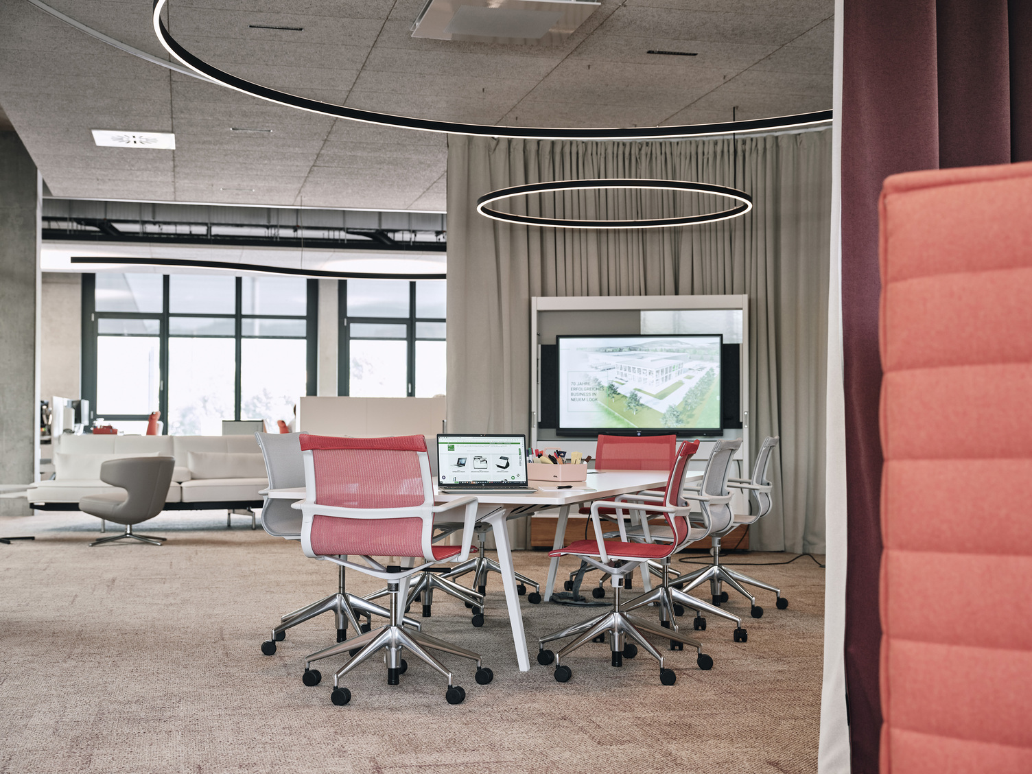 Round meeting area at Streit, featuring a central seating arrangement and Sattler's Doppio lighting fixture with direct and indirect light emission. In the background is a curved Duetto special luminaire, also with direct indirect light.