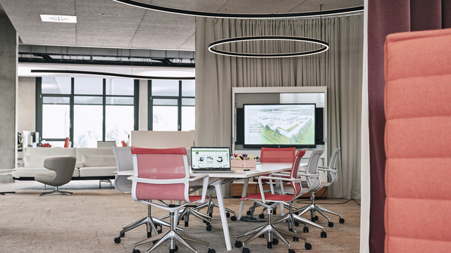Round meeting area at Streit, featuring a central seating arrangement and Sattler's Doppio lighting fixture  with direct and indirect light emission.  In the background is a curved Duetto special luminaire, also with direct indirect light.  | ©  Christoph-Duepper