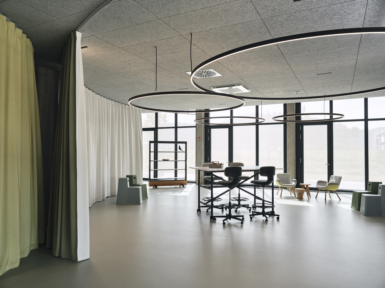 Verschiedene Doppio Direct / Indirekt Leuchten der Firma SATTLER in einem flexibel nutzbaren Bereich in einem Bürogebäude. Seien es Besprechungen, Arbeitsplätze oder Präsentationsflächen im New Work Konzept | ©  Christoph-Duepper