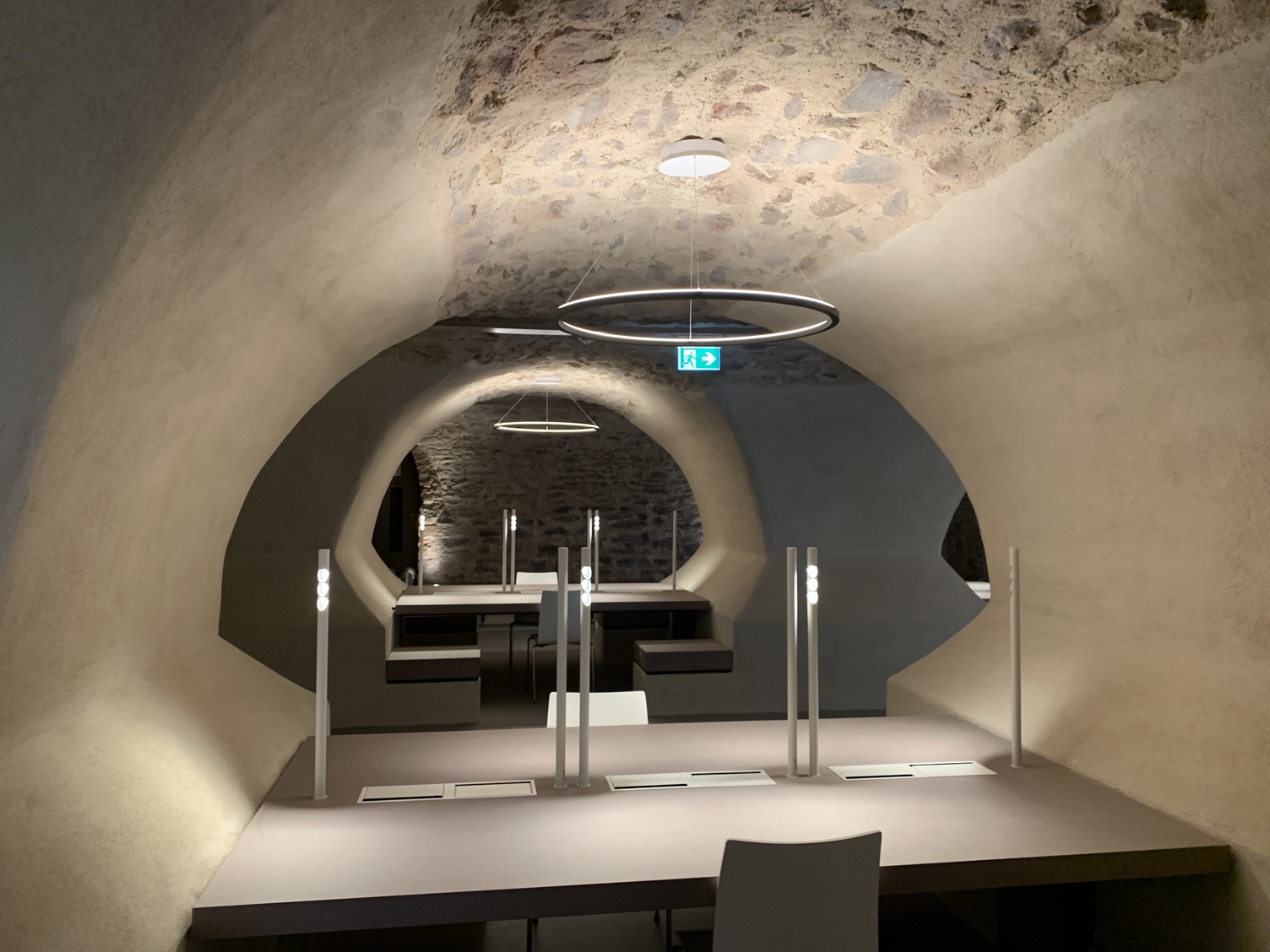TU Darmstadt Castle study room in the vaulted cellar. White tables with table lamps and additional indirect ceiling lighting provided by the Slim indirect ring pendant lights.
