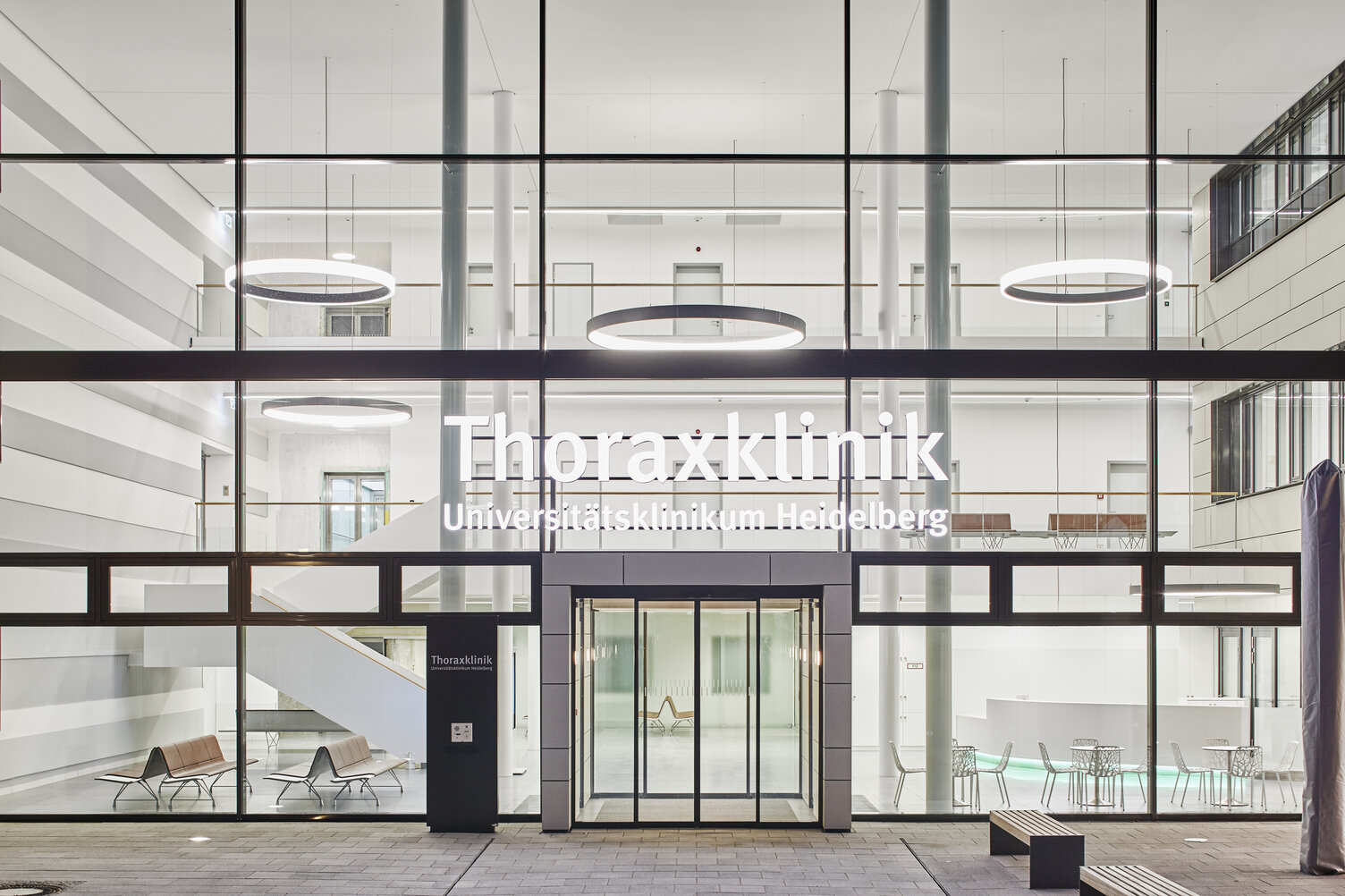 Eingangshalle & Treppenhaus Thoraxklinik mit CIRCOLO Ringleuchten | © Dietmar Strauß / Besigheim Querbild: Außenansicht durch Glasfront auf Eingangshalle der Thoraxklinik mit Säulen und großen Ringleuchten abgehangen auf verschiedene Ebenen | © Dietmar Strauß / Besigheim
