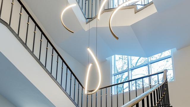 Chandelier, light object in the stairwell of a company building of the VCC Group, consisting of circular segments of SLIM ring luminaires shining inwards and the aluminum luminaire profile in gold. | © eydos GmbH