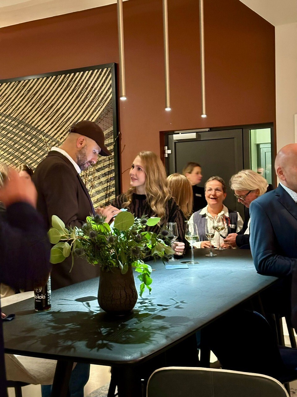 Zeigt mehrere Personen, die sich angeregt bei einem Event im SATTLERxWalter Knoll Showroom unterhalten.