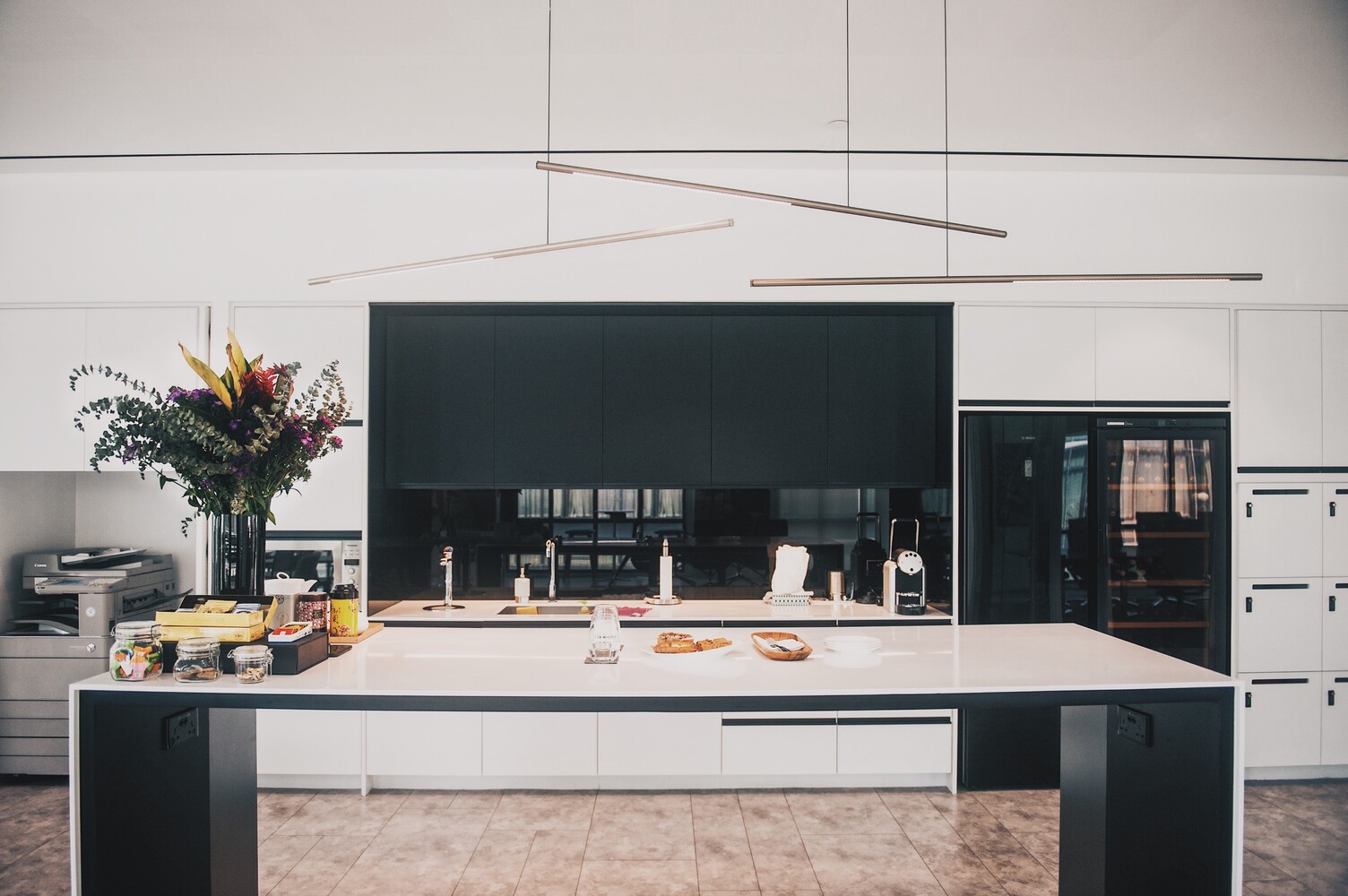 Drei Palito Pendelleuchten über einer modernen Kücheninsel im Wilkhahn Showroom Singapur