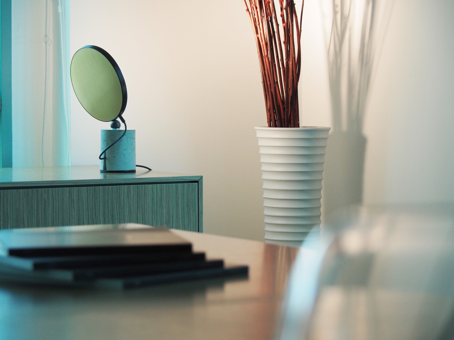 Avveni Concrete Tischleuchte mit Betonfuß auf einem Sideboard im Wilkhahn Showroom Singapur