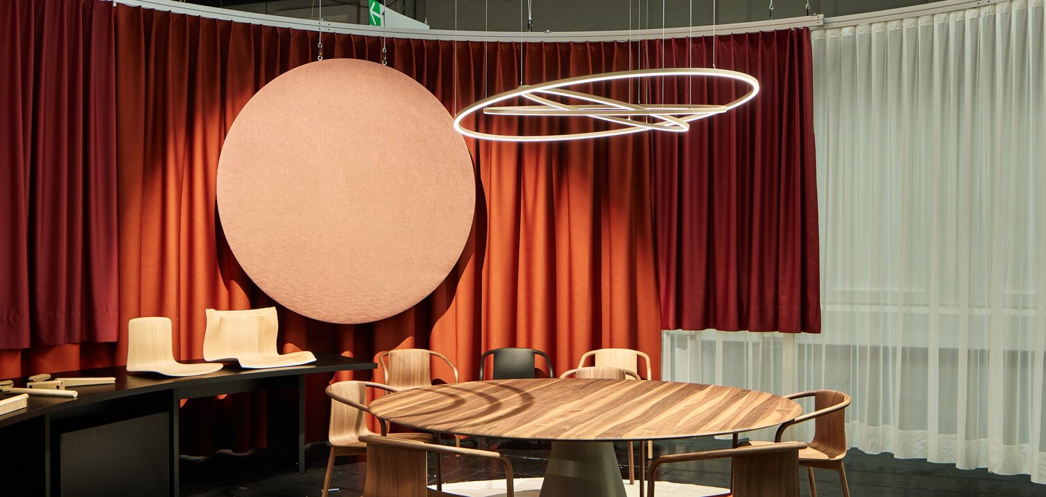 Tischsitzgruppe aus Holz von WALTER KNOLL über der eine Lichtskulptur bestehend aus drei leuchtenden Ringen abgependelt ist. | © Philip Kottlorz | Alexander Strifler