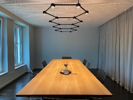 Exklusiver Meetingraum mit geometrischen, schwarzen Deckenleuchten und hochwertigem Holztisch.