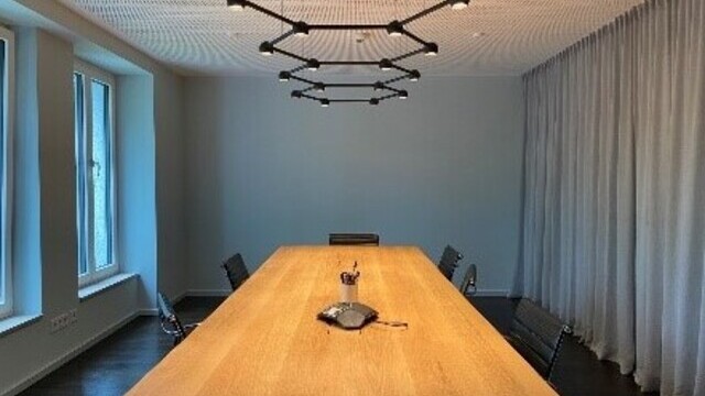Exclusive meeting room with geometric black ceiling lights and a high-quality wooden table.