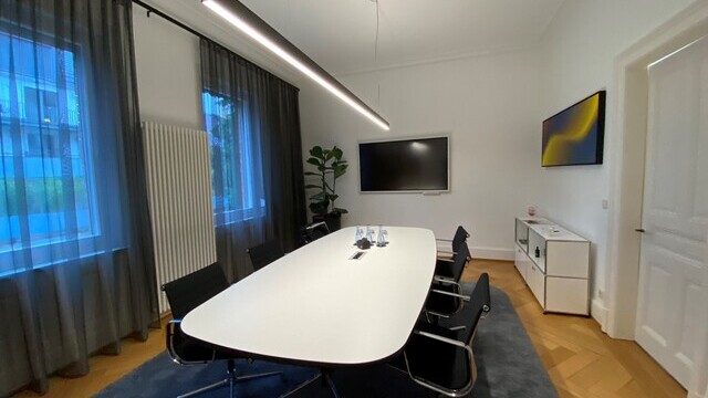 Meeting room Steuerkanzlei Matussek with linear pendant light above conference table, dark curtains | © SATTLER